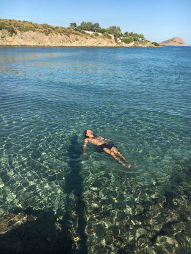 A man swimming in the turquoise waters of Andros which is without doubt one of the cheap islands in Greece.