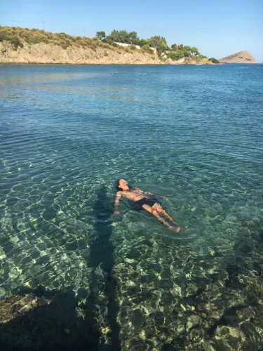 A man swimming in the turquoise waters of Andros which is without doubt one of the cheap islands in Greece.