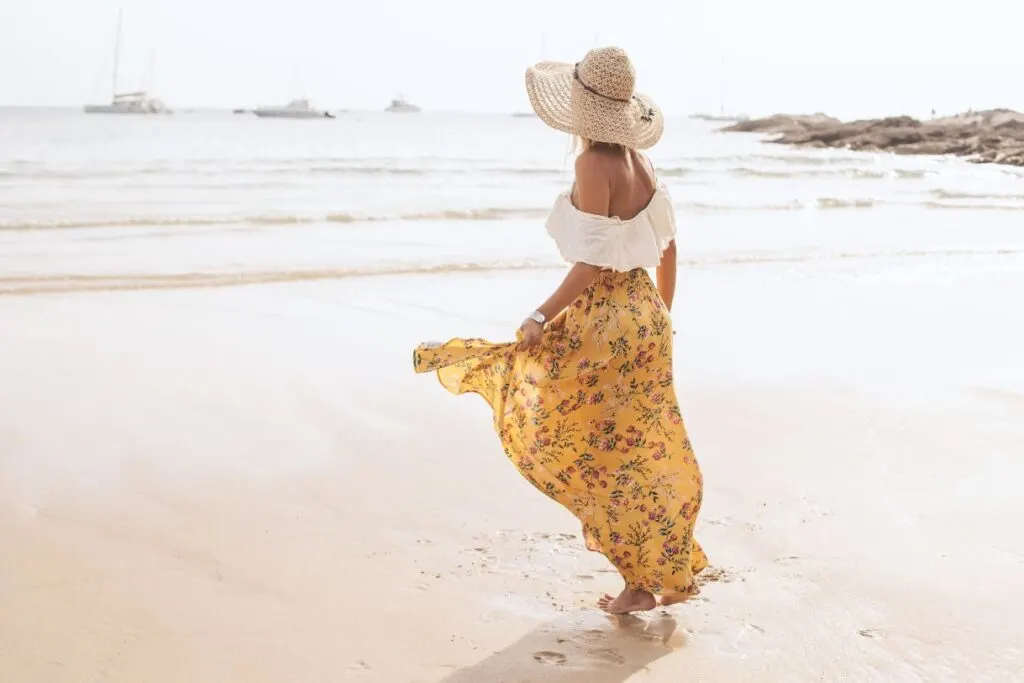 A girl with a hat and  yellow- white cotton clothing which is perfect if you are wondering what to pack for Hawaii