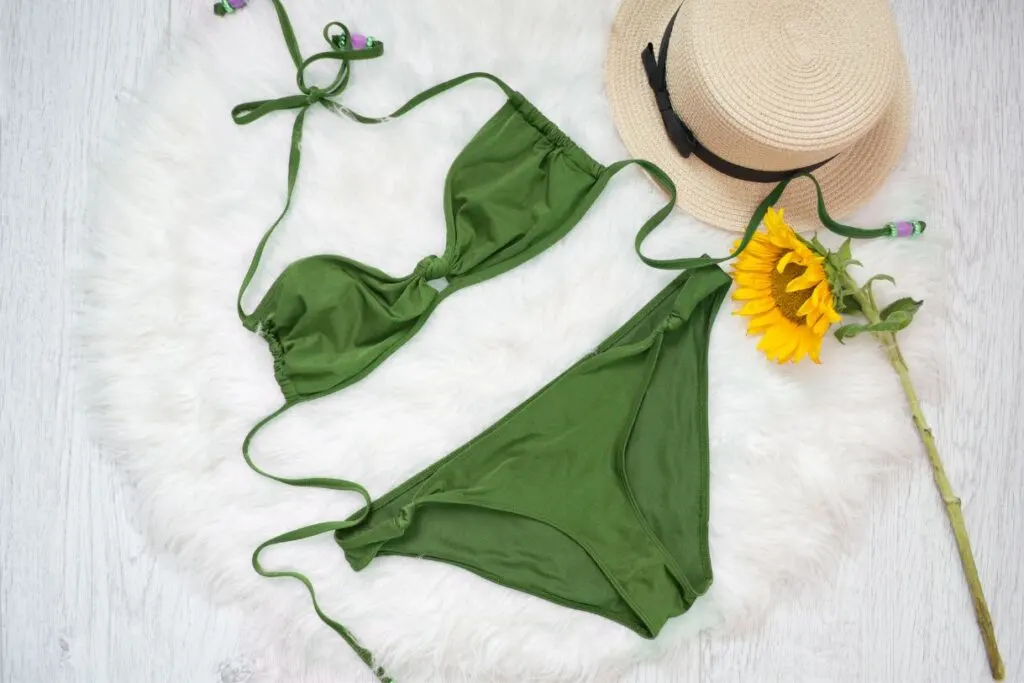 An olive green string bikini with a straw hat which is a perfect addition to any Hawaii packing list.