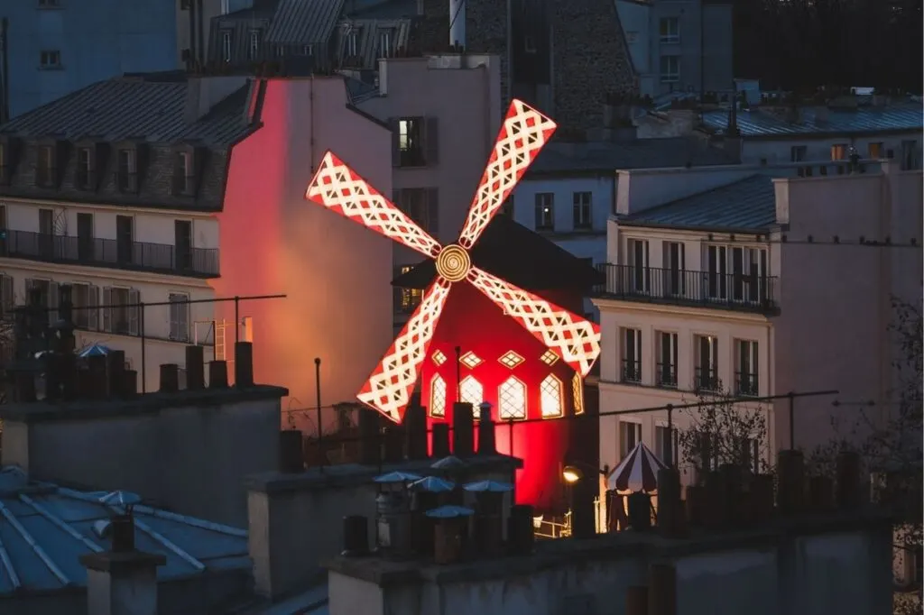 The red windmill of Moulin Rouge in the night sky. The cabaret shows are a great Paris gift experience.