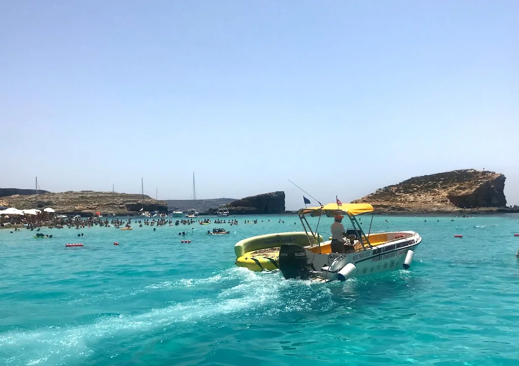 The bright blue waters in Blue lagoon with a speed boat passing through and people swimming in it should be a part of your 3 days in Malta.