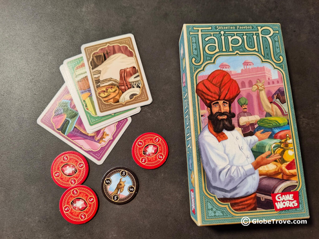 The colorful cards and tokens from the travel board game Jaipur, alongside the tiny box.