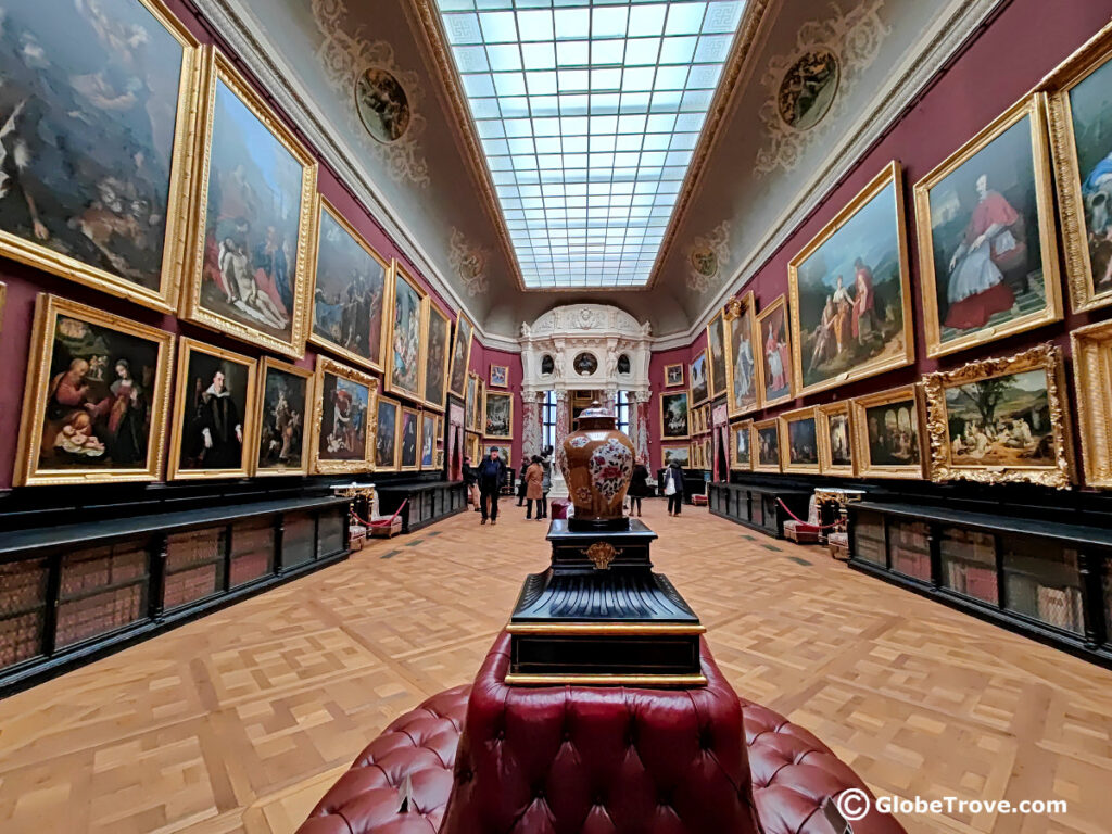 The red walls lined with ancient paintings inside the Chateau de Chantilly